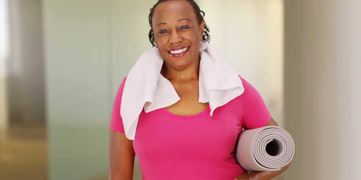 Middle-aged black woman with a yoga mat